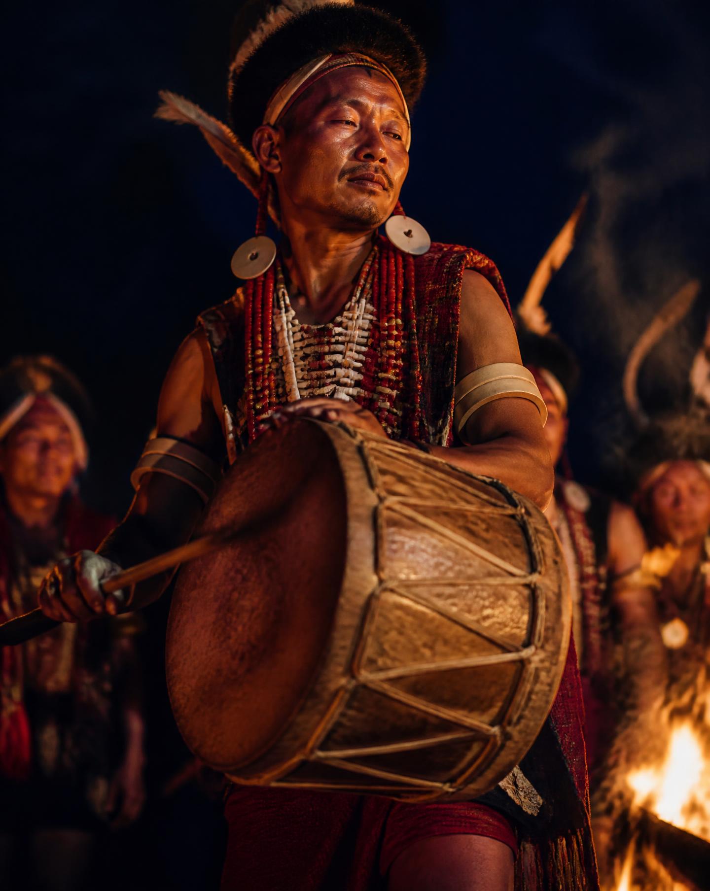 A Naga drummer performing by firelight